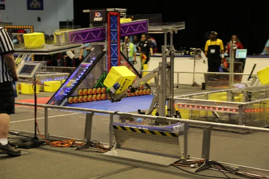 Our 2018 Robot "Don Quixote" is in action during a match at the SBPLI Regional #1, swerving across the field carrying a power cube that he looks to place on the scale.