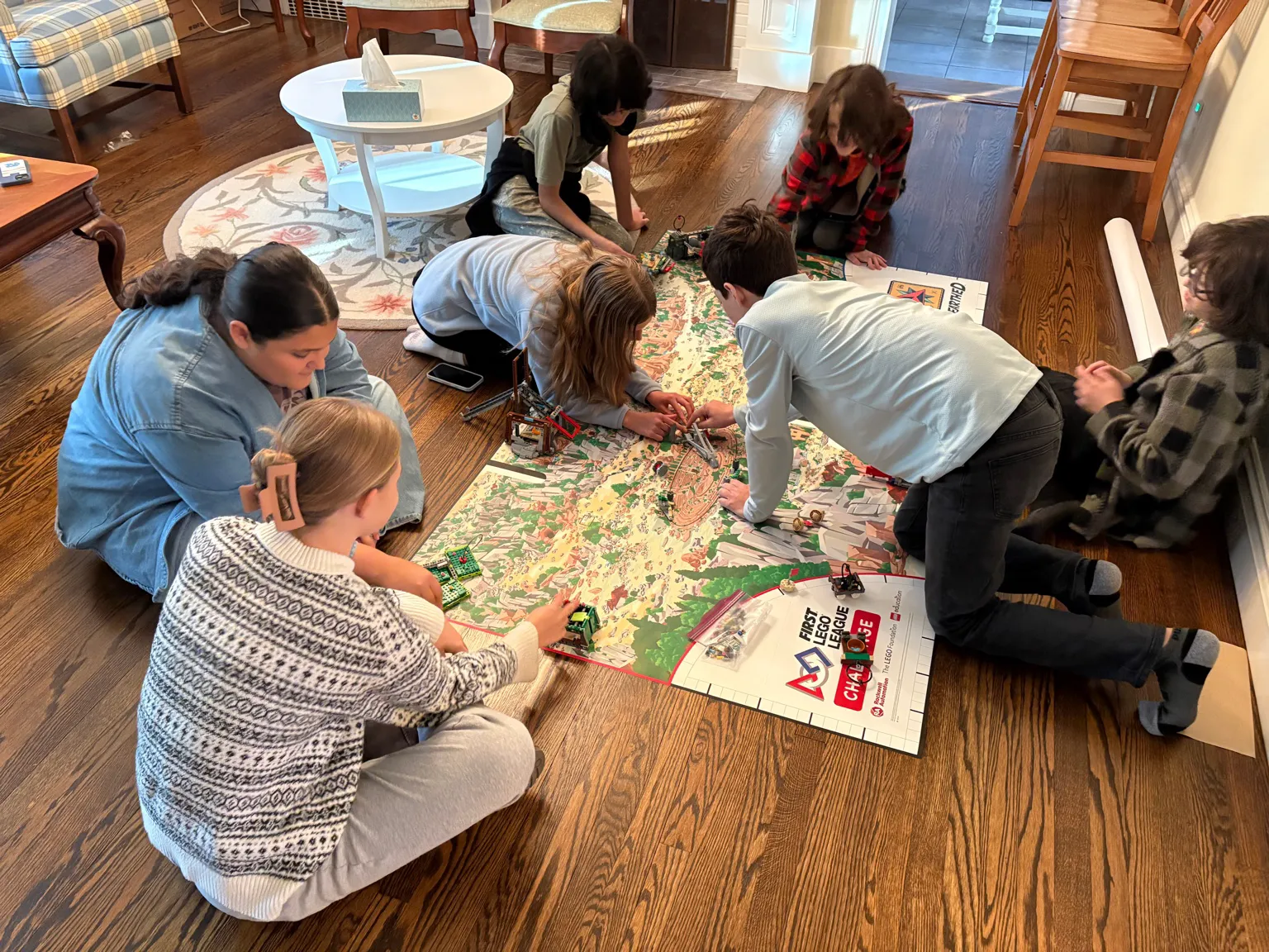 Group of students gathered around the full FLL Unearthed field